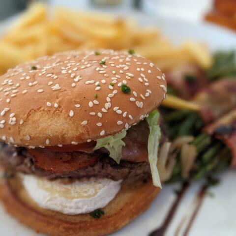 Gourmet burger with melted cheese and salad served at the Camping Le Séquoïa restaurant in the Dordogne Valley.