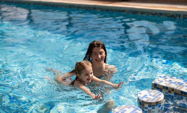 Child enjoying water games in a heated swimming pool during a family camping holiday.