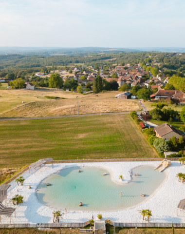 Vue aérienne du lagon naturel entouré de campagne au Camping Le Séquoïa à Payrac, au cœur de la vallée du Lot et de la Dordogne.