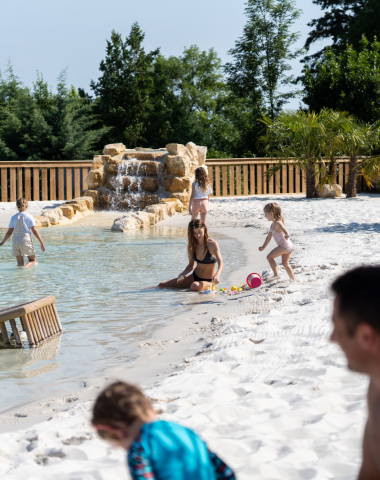 Famille profitant de la lagune naturelle et de sa plage de sable au Camping Le Séquoïa, dans la Vallée de la Dordogne.