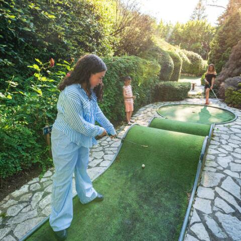 Vacanciers jouant au mini-golf au Camping Le Séquoïa, entouré de verdure.