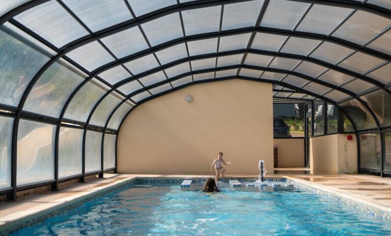 Une piscine intérieure chauffée sous un dôme transparent, idéale pour se détendre en toute saison. La structure protégée permet aux familles de profiter de la baignade même lorsque la météo est fraîche.