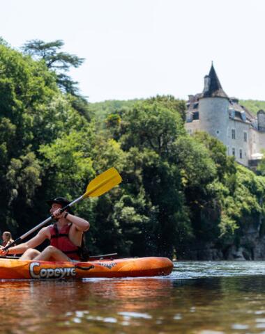 Couple en canoë sur la rivière Dordogne avec un château en arrière-plan, près de La Roque-Gageac et du Camping Le Séquoïa