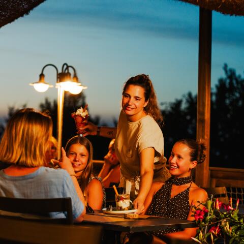 Famille partageant un repas en terrasse au restaurant du camping Le Séquoïa