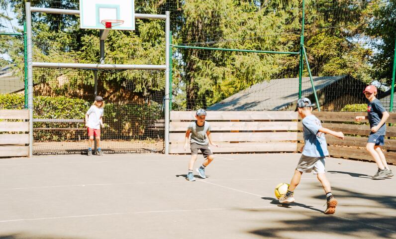 Enfants jouant au football sur le terrain multisports du camping Le Séquoïa