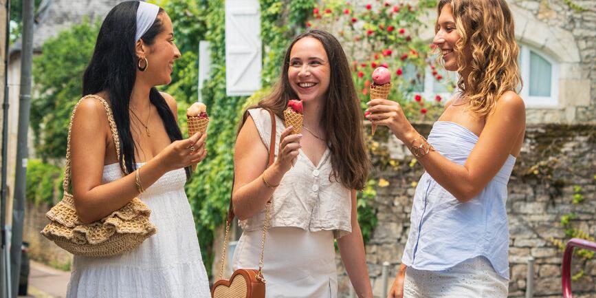 Drie vriendinnen genieten van een ijsje op een zonnige dag in een charmant dorpje bij Camping Le Séquoïa in de Dordognevallei.