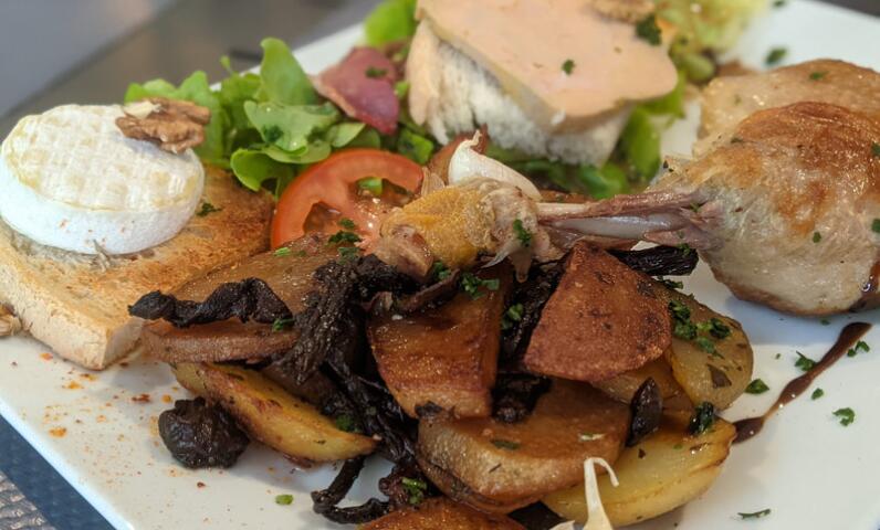 Bord met lokale gastronomische gerechten geserveerd in het restaurant van Camping Le Séquoïa, met foie gras, eendenbout, aardappelen en paddenstoelen uit de Dordognevallei.