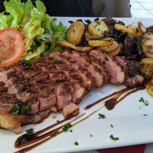 Gegrild vleesgerecht met friet en salade, geserveerd in het restaurant van Camping Le Séquoïa in de Dordognevallei.