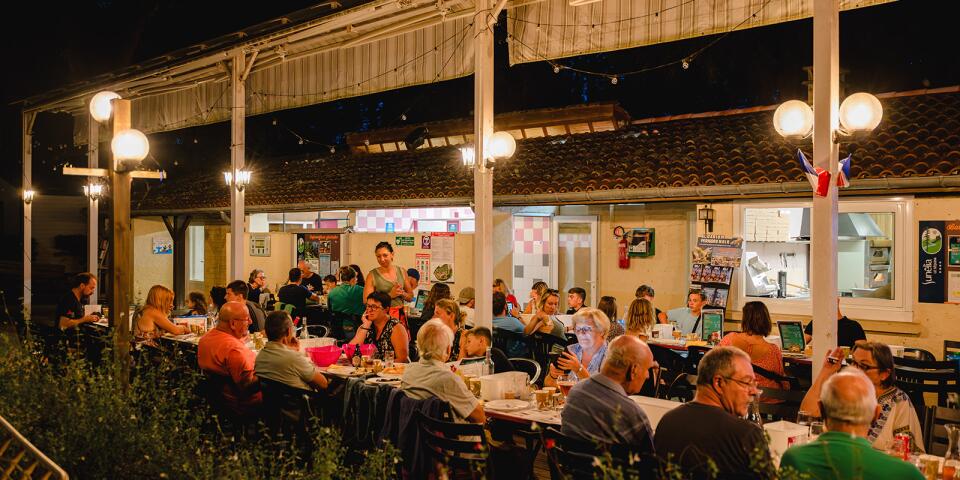Thema-avond in het restaurant van Camping Le Séquoïa, waar gasten genieten van mosselen met friet op het terras in een gezellige zomerse sfeer.