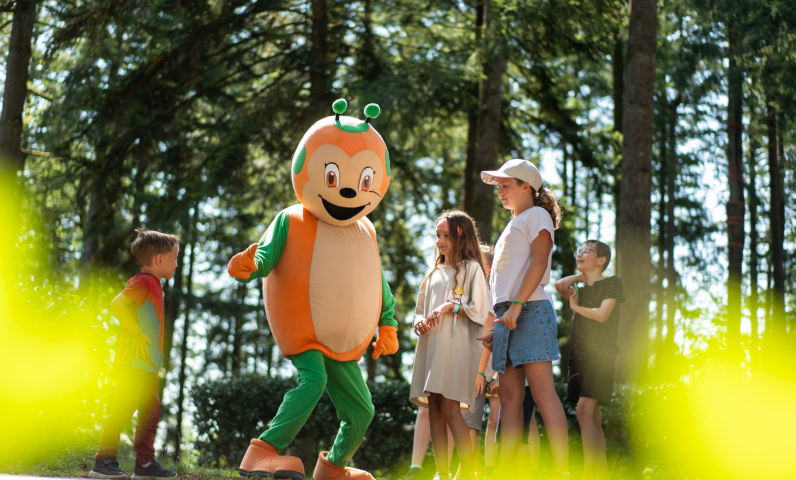 De Sunêlia-mascotte begroet kinderen op Camping Le Séquoïa in het bos van de Dordogne.