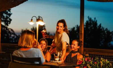 Gezin geniet samen van een maaltijd op het terras van Camping Le Séquoïa
