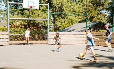 Kinderen spelen voetbal op het multisportterrein van Camping Le Séquoïa