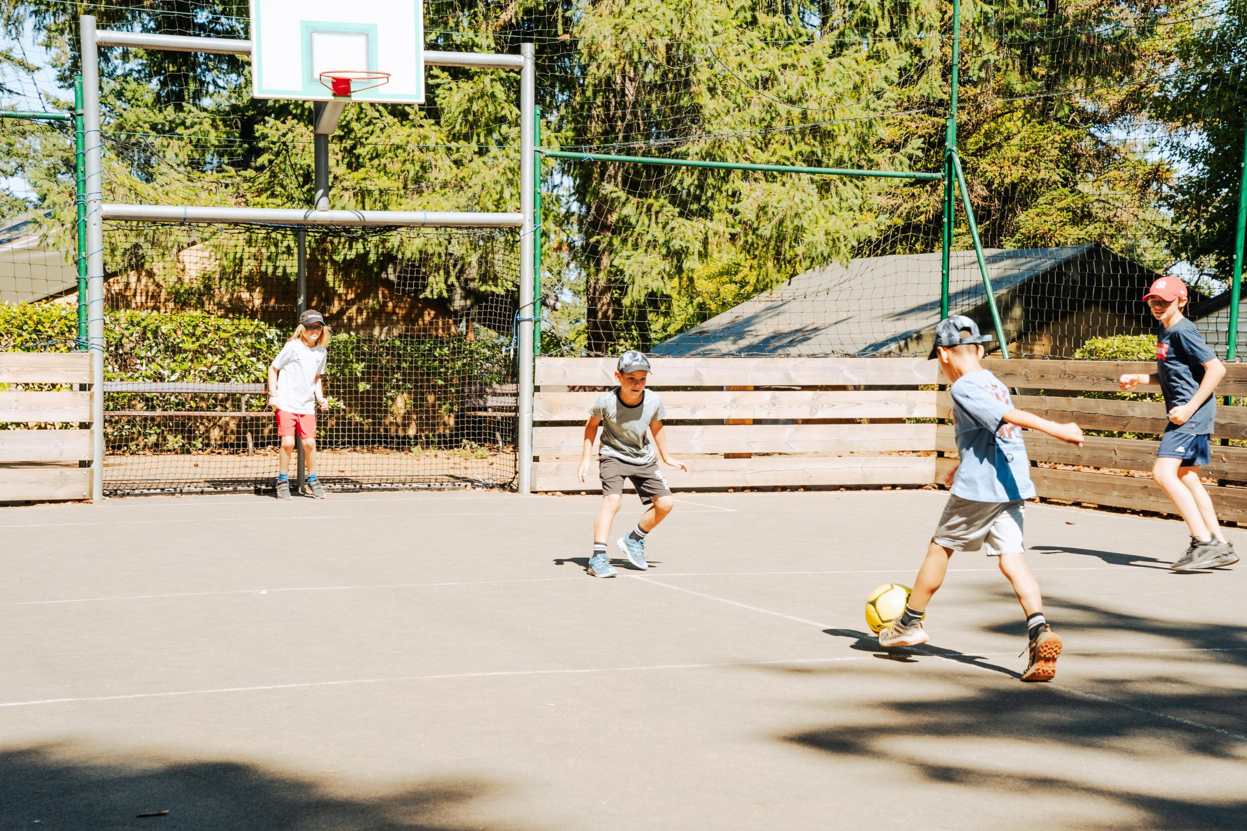 Kinderen spelen voetbal op het multisportterrein van Camping Le Séquoïa